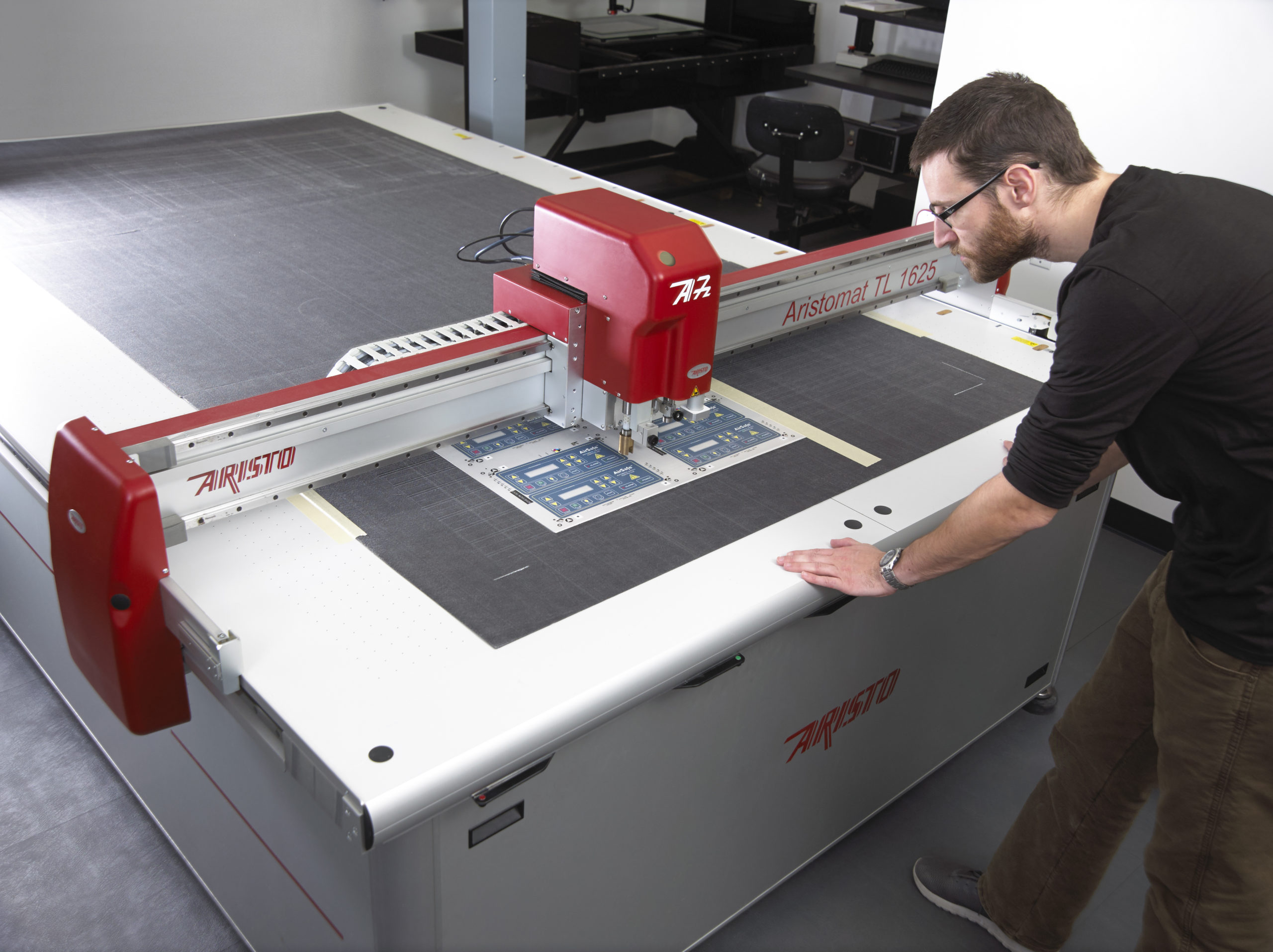 Technician using automated flatbed die cutter Technician using automated flatbed die cutter