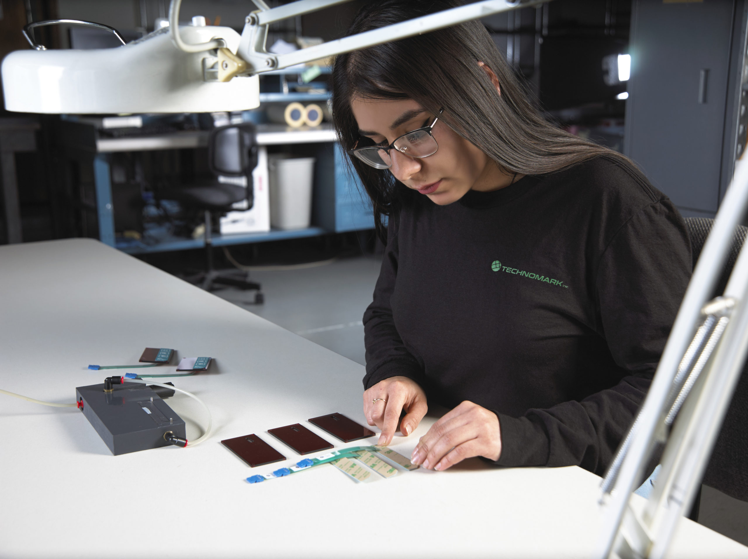 Technician applying adhesive backed switch to an overlay Technician applying adhesive backed switch to an overlay